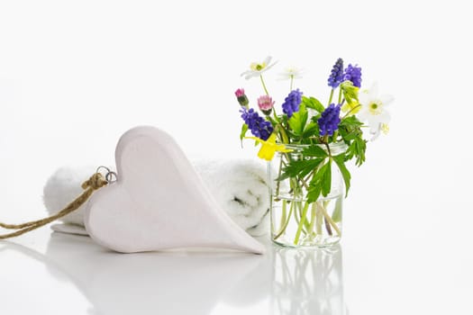White towels with heart on a white background with flowers in a vase. Spring.