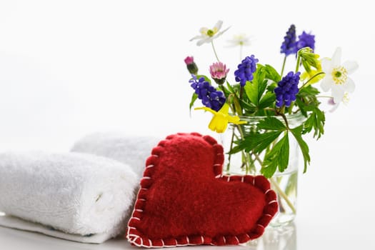 White towels with heart on a white background with flowers in a vase. Spring.