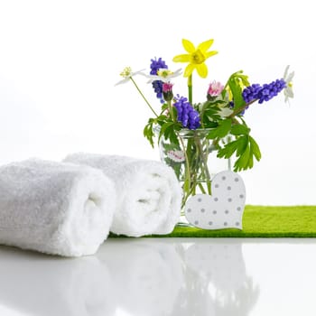 White towels with heart on a white background with flowers in a vase. Spring.