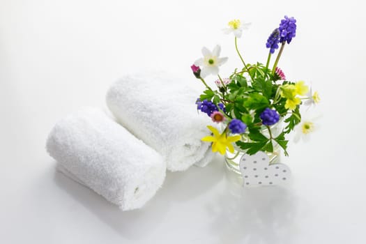 White towels with heart on a white background with flowers in a vase. Spring.
