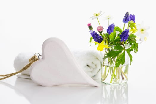 White towels with heart on a white background with flowers in a vase. Spring.