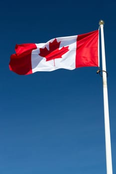 The Canadian Flag on a Falgpole with a clear blue sky.
