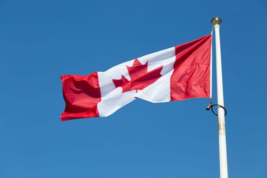 The Canadian Flag on a Falgpole with a clear blue sky.