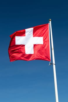 The Flag of Switzerland with a blue sky.