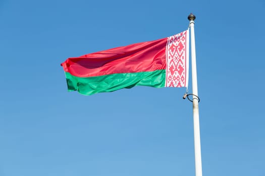 The Flag of Belarus close up with a blue sky.