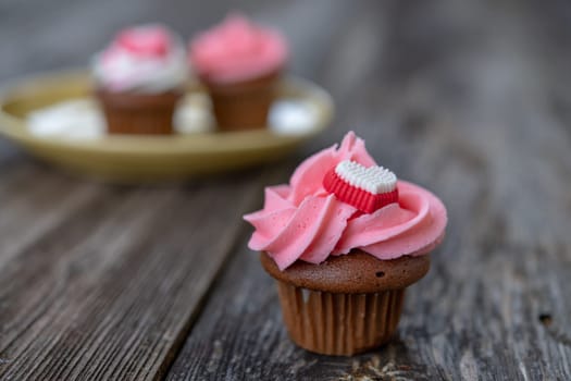 pink and white muffins on wooden ground with heart whipping cream