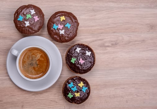 chocolate muffins with cup of coffee on wooden ground