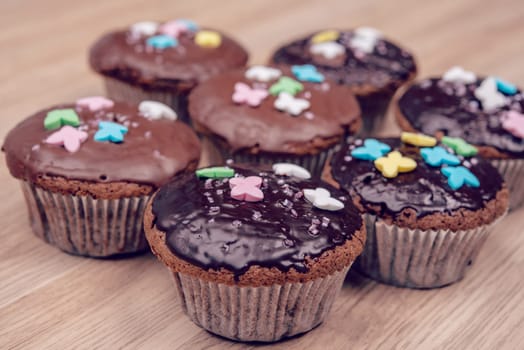 chocolate muffins with colorful decoration on wooden ground