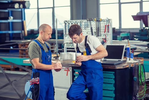 two worker in factory on work bench in conversation