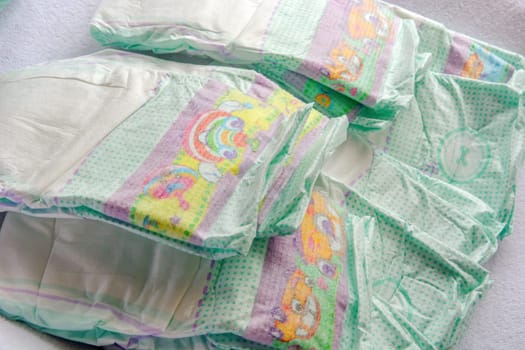 Group of disposable diapers arranged over a white changing table. Hygiene and health care for baby