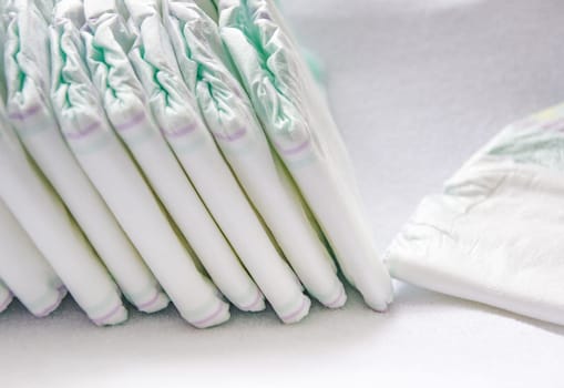 Group of disposable diapers arranged over a white changing table. Hygiene and health care for baby