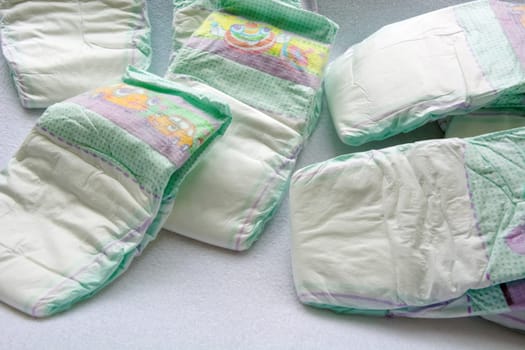 Group of disposable diapers arranged over a white changing table. Hygiene and health care for baby