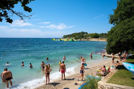Tourists and holidaymakers on the beach of the Adriatic Sea near Porec in Croatia