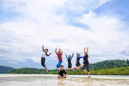 Asian traveler group adult and teens are family, Happy life enjoy by play jumping together at the beach on blue sky background, vacation in summer holiday at Ko Lipe and Ra Wi island, Tarutao, Thailand
