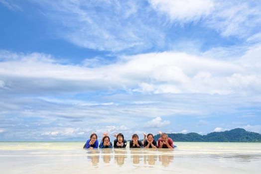 Asian people group adult and teens are family, Happy life enjoy by lying together on the beach on blue sky background, vacation in summer holiday at Ko Lipe and Ra Wi island, Tarutao, Thailand