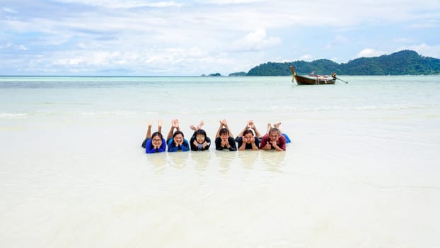 Asian people group are family, Happy life enjoy by lying together on the beach of Ra Wi island during the sea travel vacation in summer holiday at Ko Lipe, Tarutao, Satun, Thailand,16:9 widescreen