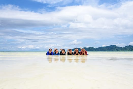 Asian people group adult and teens are family, Happy life enjoy by lying together on the beach of Ra Wi island during the sea travel vacation in summer holiday at Ko Lipe, Tarutao, Satun, Thailand