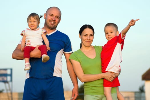 The happy family, father, mother, son and daughter are together posing outdoors.