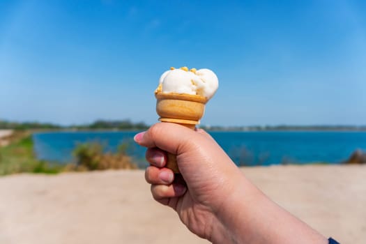Hand with ice cream on blurred blue sky nature background, Relaxation concept