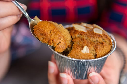 Hand women with banana cupcake in spoon on blurred background