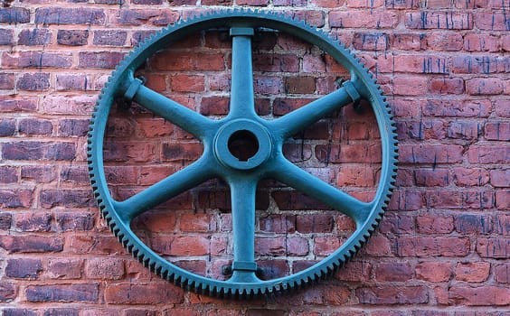 one old gear an a wall  of one hold house made of stone