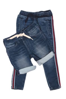 Fashionable denim clothes. Trendy stretch blue jeans trousers and a stylish short jeans pants with white ribbon isolated on a white background. Fashionable jeans for child boy.