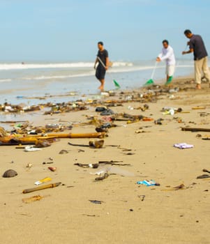 Group of people cleaning up beach from the garbage and plastic waste.