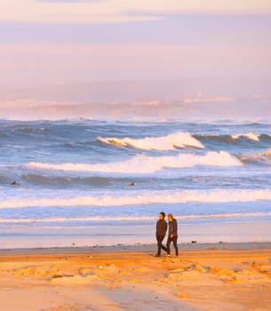PENICHE, PORTUGAL - DECEMBER 17, 2016: Young people walking by thebeach of Atlantic ocean coast in sunset light