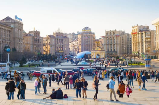 KIEV, UKRAINE - APRIL 6, 2019: Crowd of people walking at Maidan Nezalezhnosti central square in sunlight, cars traffic and shopping mall Globus glass rooftops, Kyiv, Ukraine
