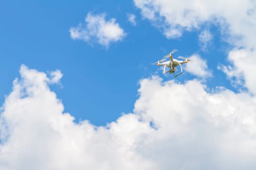 White drone quad copter with high resolution digital camera flying in the blue sky