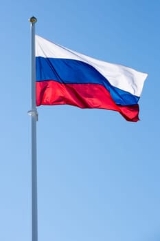 The Flag of Russia waving in the wind with a clear blue sky.