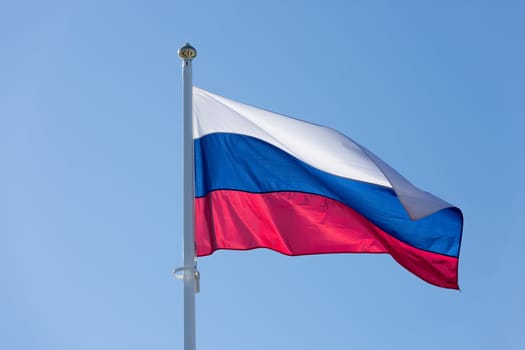 The Flag of Russia waving in the wind with a clear blue sky.