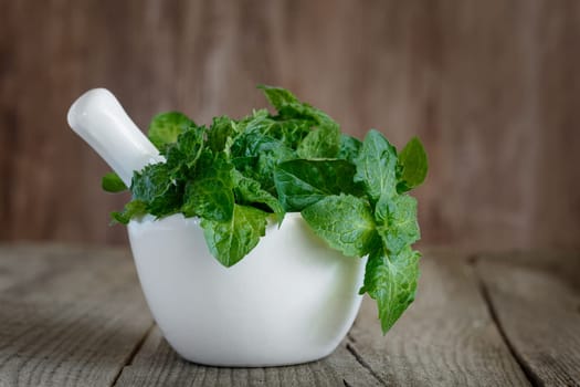 A bunch of green fresh curly mint on a wooden background