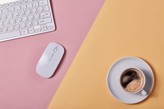 Cup of coffee, computer keyboard and mouse on background consisting of two colores pink and yellow. Top view with copy space. Design element for menu of cafe, internet cafe, web, workplace.