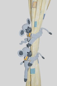 Two crocheted monkeys cling to the curtain