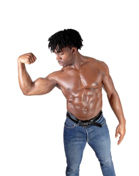 A handsome young African man standing in jeans and shirtless flexing.his biceps with his curly black hair, isolated for white background.