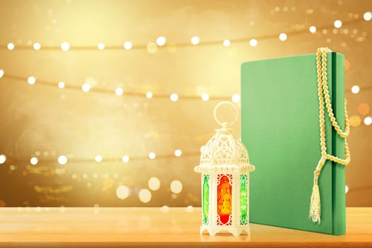 Quran with prayer beads and arabic lamp with beautiful light on wooden table with blurry lights background
