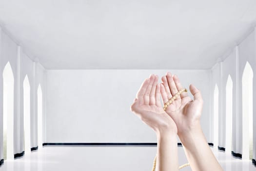 Muslim hands praying with prayer beads in the mosque