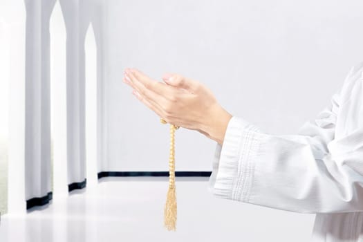 Muslim man praying with prayer beads on his hands in the mosque
