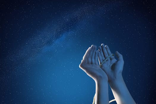 Muslim hands praying with prayer beads at outdoor with night scene background