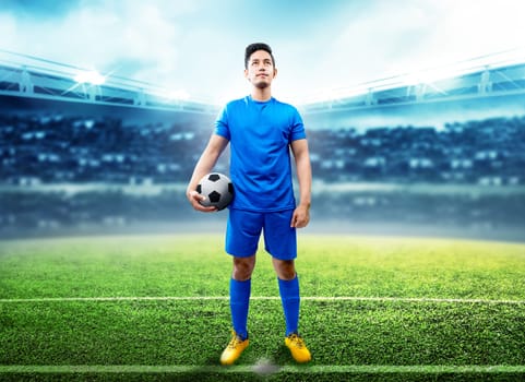 Asian football player man holding the ball in the middle of football field on stadium