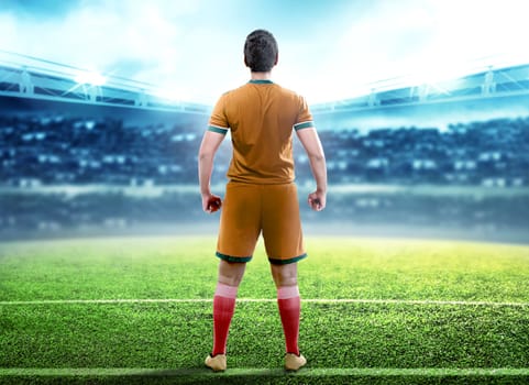 Rear view of football player man standing in the middle of football field on stadium