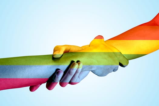 Two gay couple hands with rainbow flag skin holding each other by the wrists over bright background. LGBT concept