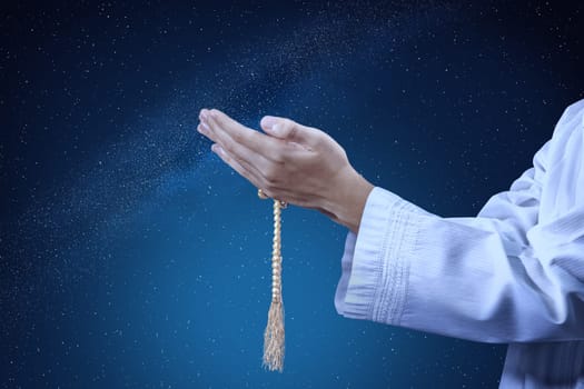 Muslim man praying with prayer beads on his hands at outdoor with night scene background