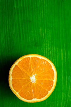 closeup of a half ripe juicy orange on green ground