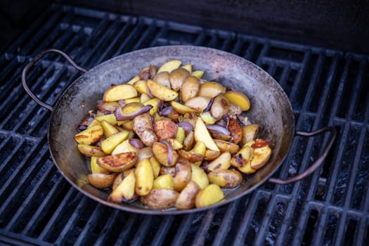 grilled potatos with onionin iron pan on barbecue