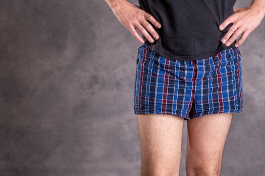 man in blue plaid boxer shorts in front of gray background