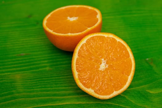 two halves of a ripe juicy orange on green ground