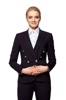 Portrait of pretty blonde in business outfit stands with folded hands.