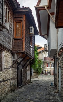Nesebar, Bulgaria - September 08, 2014: Narrow street of the old town of Nessebar. Retro houses and cobblestone pavement. UNESCO world heritage site. Vertical shot.